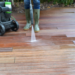 person cleaning deck with pressure wash