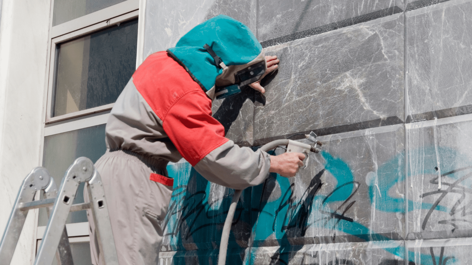 person removing graffiti on wall